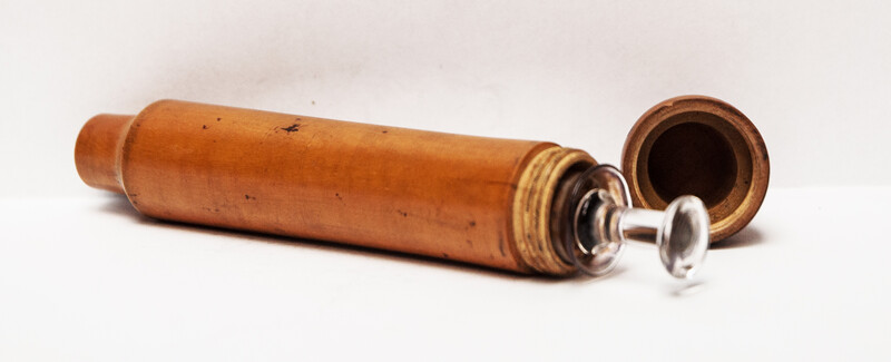 A 19th century glass syringe in its original boxwood container.