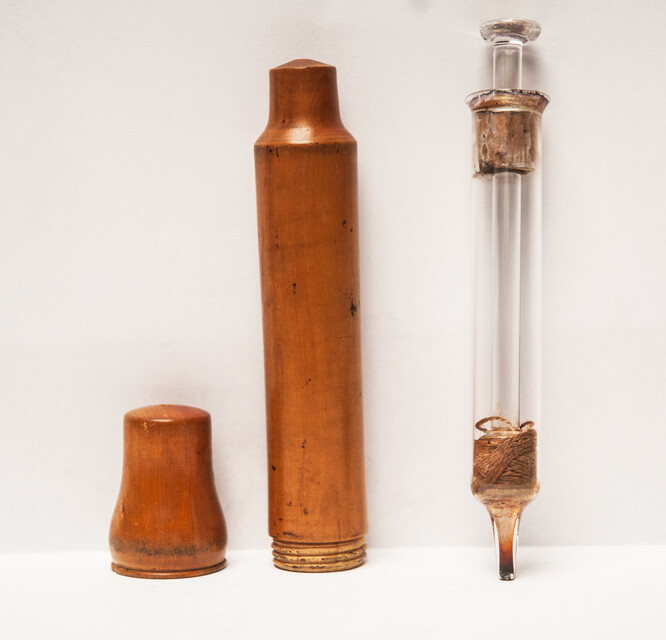 A 19th century glass syringe in its original boxwood container.