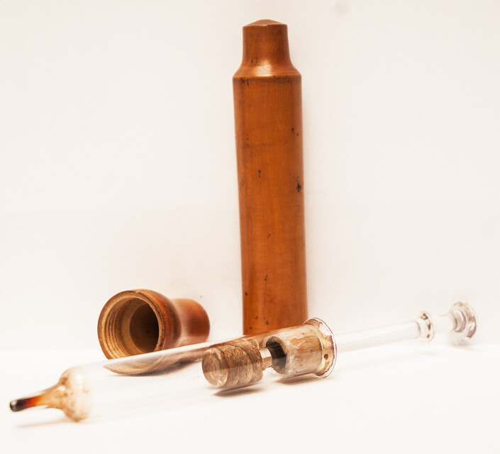 A 19th century glass syringe in its original boxwood container.