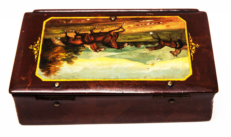 A paper mache tobacco box with a beautifully painted landscape with horses.