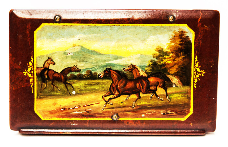 A paper mache tobacco box with a beautifully painted landscape with horses.