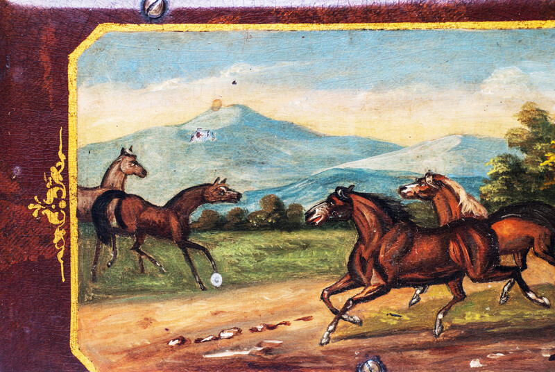 A paper mache tobacco box with a beautifully painted landscape with horses.