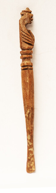 A seventeenth century bone ear-spoon crowned by a man with a hat.