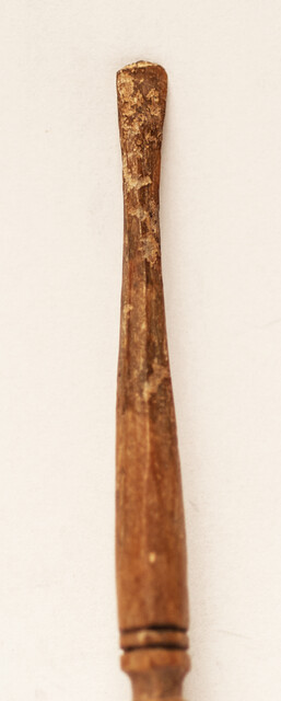 A seventeenth century bone ear-spoon crowned by a man with a hat.