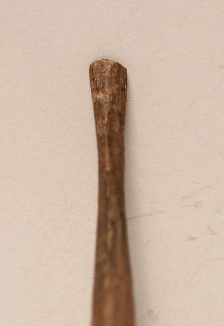 A seventeenth century bone ear-spoon crowned by a man with a hat.