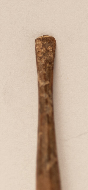 A seventeenth century bone ear-spoon crowned by a man with a hat.