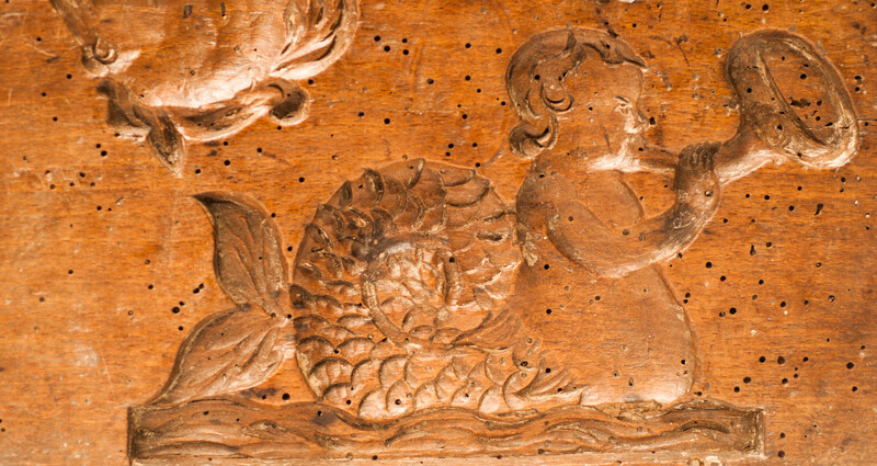 An eighteenth century double sided cookie mould with mythological creatures on one side and a man with a horse on the other side.